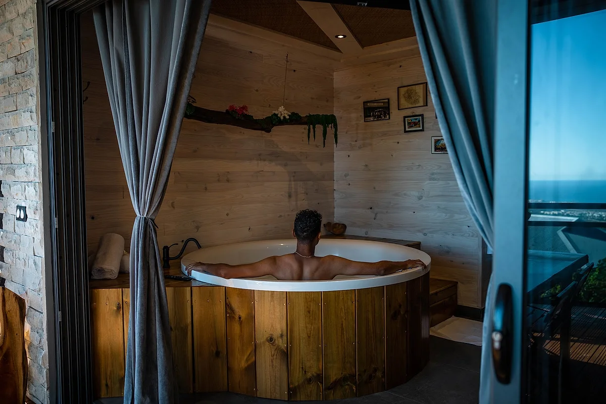 Un bain chaud dans une cuve en bois, à l'abri d'un rideau