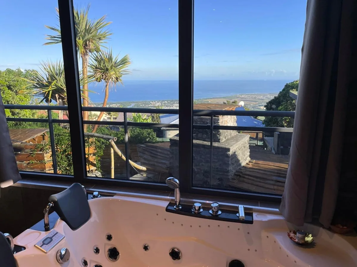 La baignoire balnéo du Bananier devant la baie vitrée et la mer