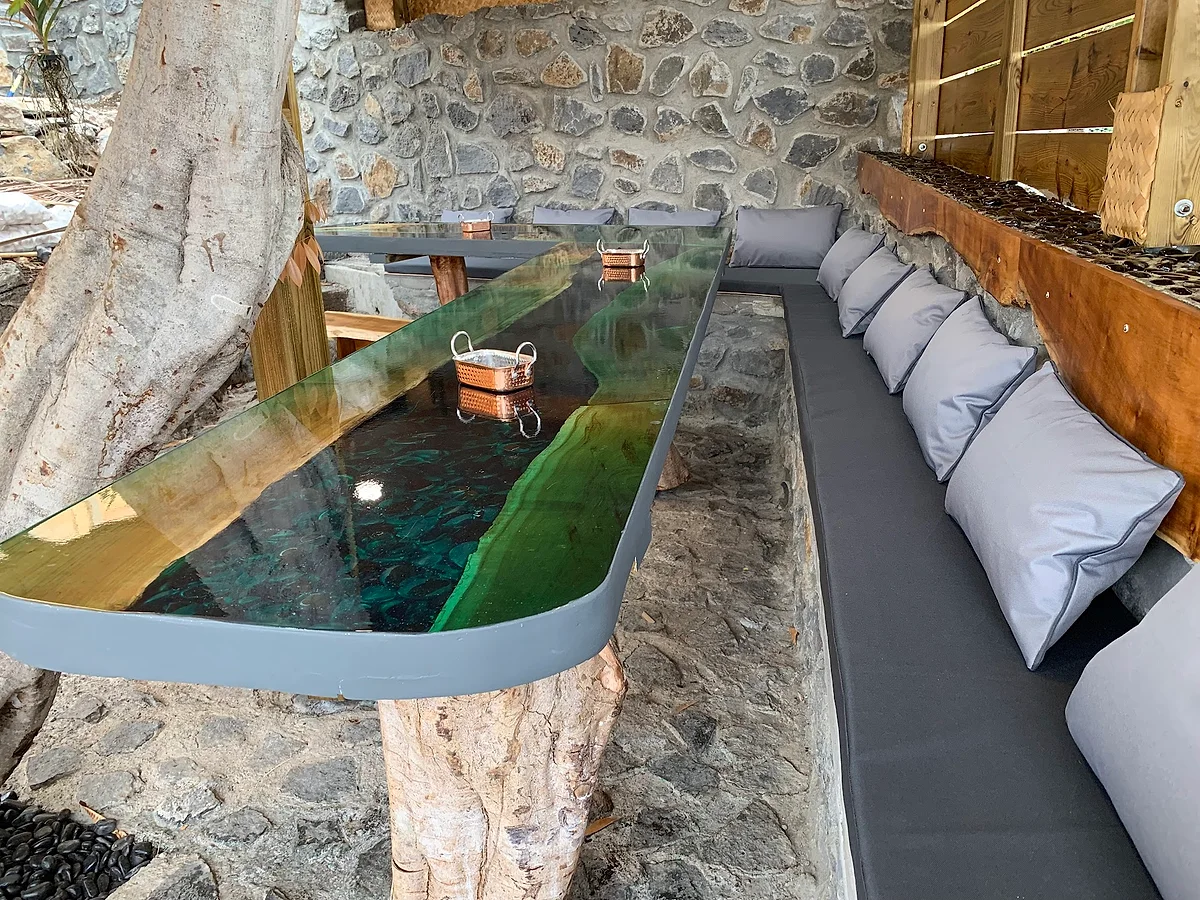Une table en bois et résine verte devant un mur de basalte